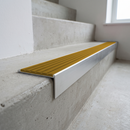 Slimline raked back 59x30mm aluminium stair nosing with a golden amber ribbed PVC insert, on a satin aluminium bar, fitted directly to a bare concrete step