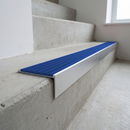Slimline raked back 59x30mm aluminium stair nosing with a mid blue ribbed PVC insert, on a satin aluminium bar, fitted directly to a bare concrete step