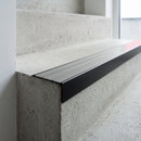 Slimline raked back 59x30mm aluminium stair nosing with a pale polar grey ribbed PVC insert, on a black anodised bar, fitted directly to a bare concrete step