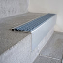 Concealed-fix aluminium stair nosing 65x55mm square front with a polar grey castellated PVC cover strip, fitted to a concrete step