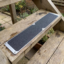 Black 115 x 635mm flat anti-slip plate screwed onto the tread of a timber garden step