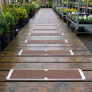 Brown anti-slip aluminium plates screwed across a timber boardwalk in a garden centre plant area