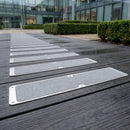 Grey grit anti-slip plates fixed across a dark composite decking path in an office courtyard
