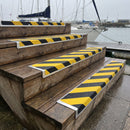 Black and yellow hazard stripe anti-slip nosing plates screwed to timber steps down to a marina pontoon