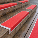 Red anti-slip aluminium nosing plates screwed to timber decking steps outside a cafe