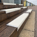 White anti-slip nosing plates on dark timber steps at a seaside cafe terrace