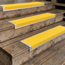 Yellow grit step nosing plates on timber steps at an industrial unit door