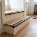 Antique brass 89mm ribbed stair nosings fitted to two oak steps with cream risers in a hallway