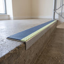 Aluminium stair nosing 56x32mm with photoluminescent strip and a cobalt blue anti-slip PVC insert, fitted to a concrete step