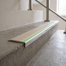 Ramped aluminium stair nosing 66x32mm with photoluminescent strip and a beige anti-slip PVC insert, fitted to a concrete step