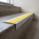 Ramped aluminium stair nosing 66x32mm with photoluminescent strip and a yellow anti-slip PVC insert, fitted to a concrete step