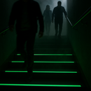 Photoluminescent stair tape glowing during emergency evacuation — green glow guides safe descent