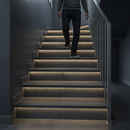 Heavy duty tile-in stair nosing in Black installed on tiled UK staircase with person using the stairs - real-life use case