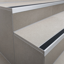 Tile-in aluminium stair nosing with black silicone carbide anti-slip insert on a finished tiled staircase