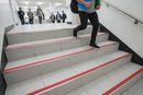 Anti-slip aluminium stair nosing with Red PVC insert — installed on UK staircase with person using the stairs