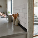Modern kitchen with white subway tiles and concrete countertop showcasing seamless PVC tile trim edges