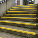 Yellow GRP anti-slip stair nosing installed on concrete outdoor steps at UK school entrance