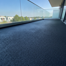 Black TerraceShield anti-slip balcony paint applied to a balcony floor, a modern minimalist balcony with glass balustrade