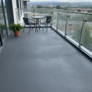 Charcoal TerraceShield anti-slip balcony paint applied to a balcony floor, a modern apartment balcony with a small bistro table and two chairs