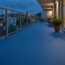 Mid Blue TerraceShield anti-slip balcony paint applied to a balcony floor, a city apartment balcony in the evening with warm lighting