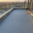 Mid Grey TerraceShield anti-slip balcony paint applied to a balcony floor, a rooftop terrace overlooking a city skyline at golden hour