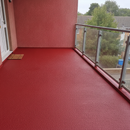 Red TerraceShield anti-slip balcony paint applied to a balcony floor, a communal walkway and landing outside flats