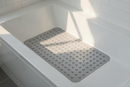 Clear transparent non-slip suction bath mat laid inside a bright modern bathtub