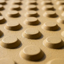 Close-up of buff tactile paving showing raised flat-topped blisters and matte gritted GRP texture