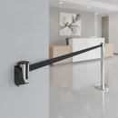 Stainless steel wall-mounted retractable belt post with a black belt extended to a stanchion post in a corporate office reception
