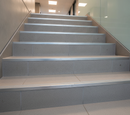 Silver aluminium step nosing on commercial tiled stairs in UK office building - anti-slip grooved surface