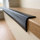 Close-up of the ribbed tread and rounded bullnose edge of black 50x25mm PVC stair nosing on an oak step