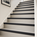 Black self-adhesive PVC stair nosing 50x48mm on each step of a pale grey painted staircase in a UK home