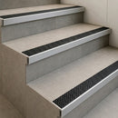 Tile-in stair nosings with black anti-slip inserts set flush into grey tiled steps