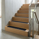 Black inserts fitted to oak timber stairs in a bright interior with glass and steel balustrade