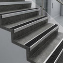 Black anodised aluminium raked back nosings with black ribbed inserts on dark concrete steps