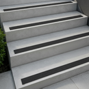 Black dovetail non-slip inserts set into pale grey concrete outdoor steps