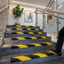 Black and yellow hazard-striped GRP stair nosings on grey steps in an office stairwell