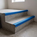 Blue GRP anti-slip stair nosings fitted to the front edge of concrete steps in a stairwell