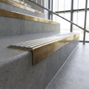Solid brass stair nosing, 59.5mm tread with a 30mm square front, in Antique Brass finish with Light Grey Castellated insert, fitted to a staircase