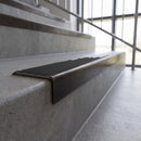 Solid brass stair nosing, 59.5mm tread with a 30mm square front, in Antique Bronze finish with Black Smooth Textured insert, fitted to a staircase