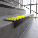 Solid brass stair nosing, 59.5mm tread with a 30mm square front, in Antique Bronze finish with Yellow Castellated insert, fitted to a staircase