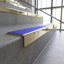 Solid brass stair nosing, 59.5mm tread with a 30mm square front, in Polished Brass finish with Mid Blue Castellated insert, fitted to a staircase