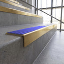 Solid brass stair nosing, 59.5mm tread with a 30mm square front, in Satin Brass finish with Mid Blue Castellated insert, fitted to a staircase