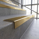 Solid brass stair nosing, 59.5mm tread with a 30mm square front, in Satin Brass finish with Olive Castellated insert, fitted to a staircase