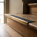 BN71SLR solid brass stair nosing in Antique Brass finish with Black Olympic Grip insert, fitted to a step edge