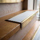 BN71SLR solid brass stair nosing in Antique Brass finish with Light Grey Castellated insert, fitted to a step edge
