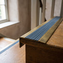 BN71SLR solid brass stair nosing in Antique Brass finish with Mid Blue Castellated insert, fitted to a step edge