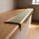 BN71SLR solid brass stair nosing in Antique Brass finish with Olive Castellated insert, fitted to a step edge