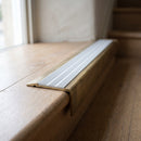 BN71SLR solid brass stair nosing in Antique Brass finish with Polar Grey Castellated insert, fitted to a step edge