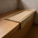 BN71SLR solid brass stair nosing in Antique Brass finish with Porth Stone Castellated insert, fitted to a step edge